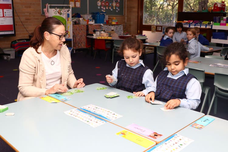 Two students working at a table with a teacher.