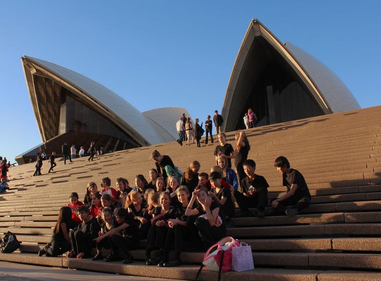 Students from Normanhurst Public School choir sitting on the steps of the Sydney Opera House before a performance.