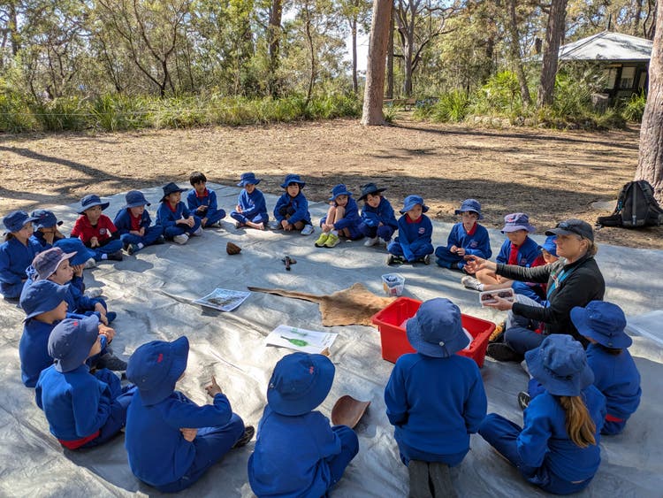 Agroup of students sitting in a yarning circle on an excursion.