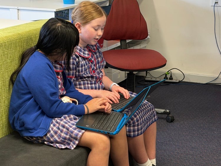 Students writing in the school library using laptops.