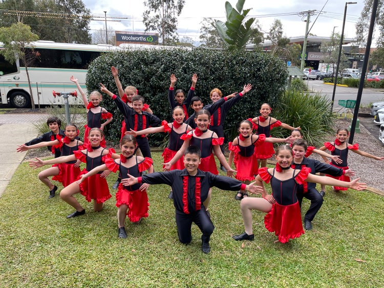 A group of students dressed in red and black dance costumes.